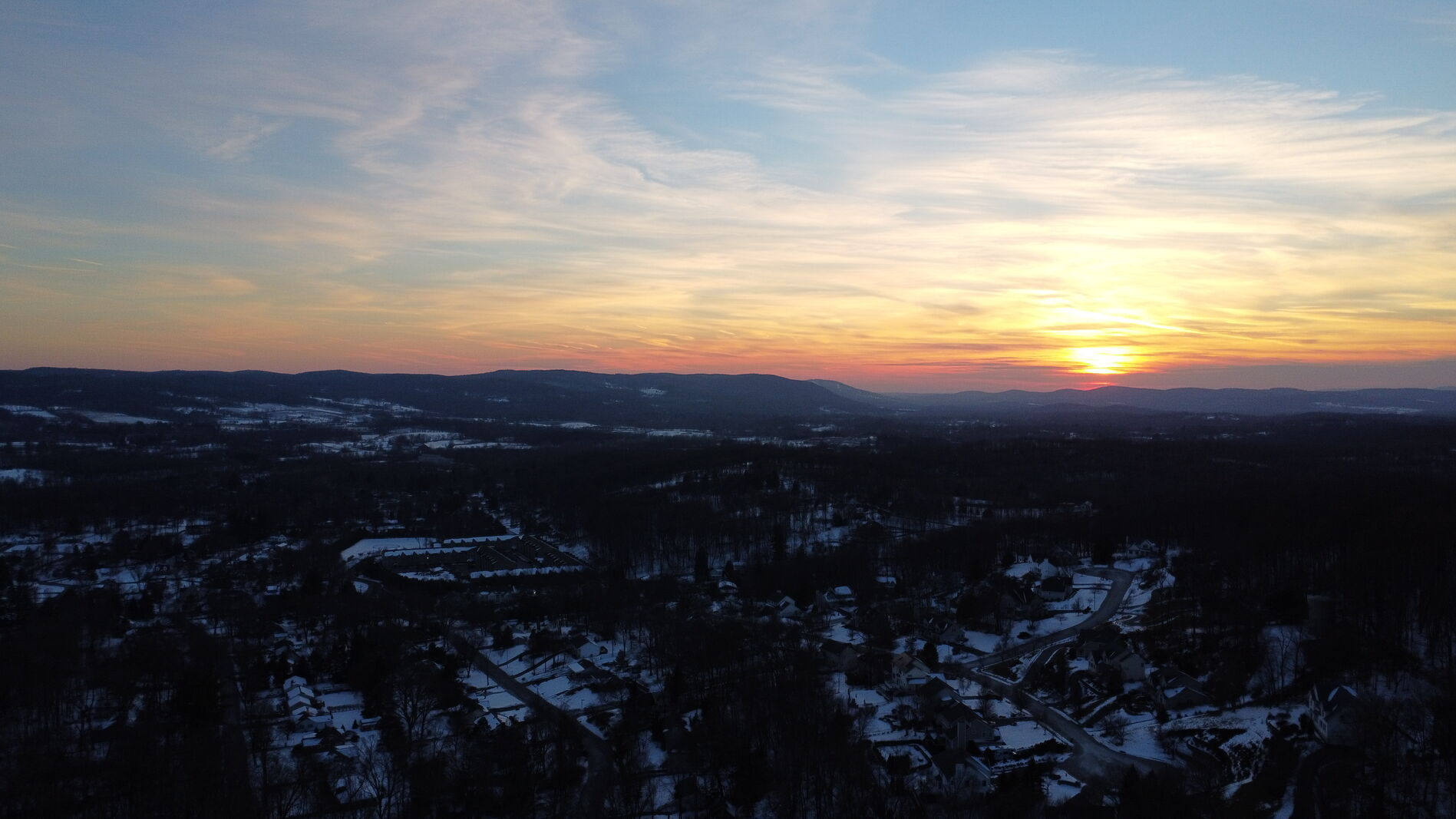 Aerial dawn horizon panorama with distant city lights below.