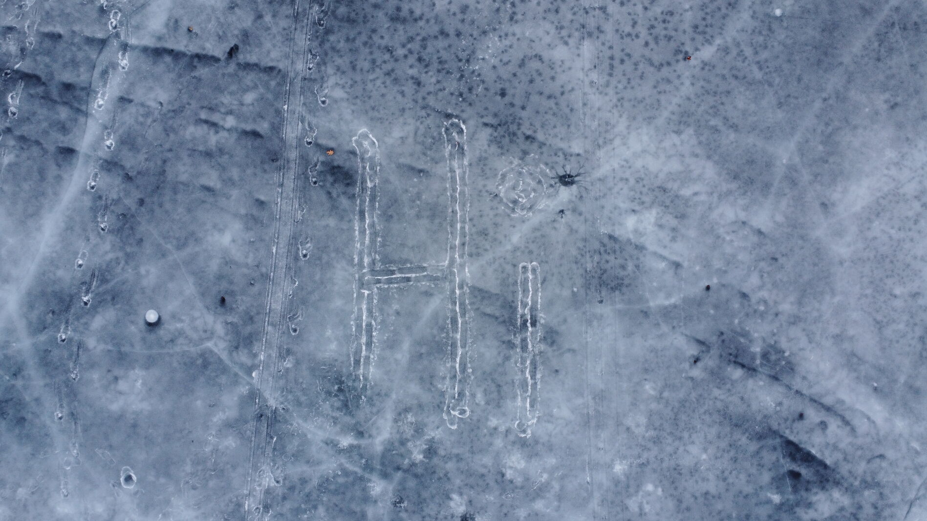 Top-down view of cracked ice on a frozen lake, near-monochrome geometry.